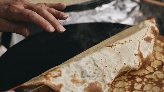 Une femme retourne une crêpe bretonne cuite sur une billig
