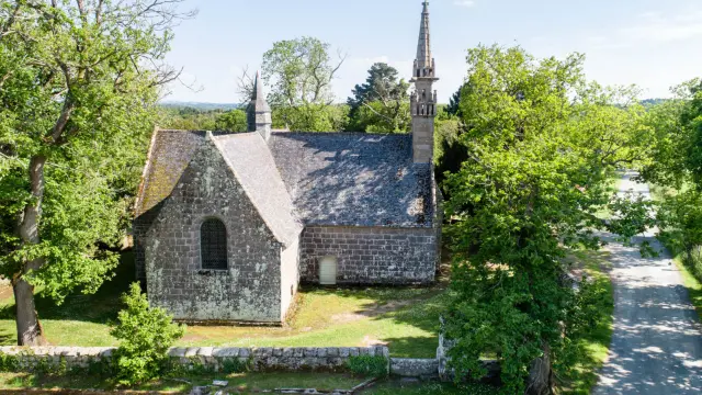 Photo de la Chapelle des Sept Saints entourée de son muret et d'arbres avec un chemin de terre situé au côté droit