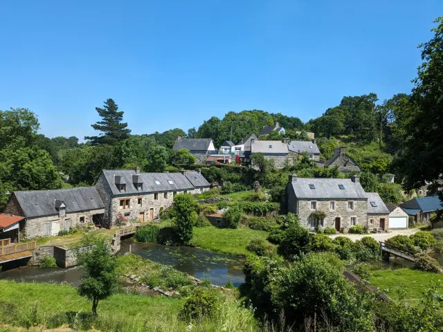 Vue sur plusieurs habitations du hameau du Guindy, entouré de nature et surplombant une rivière avec un ponton