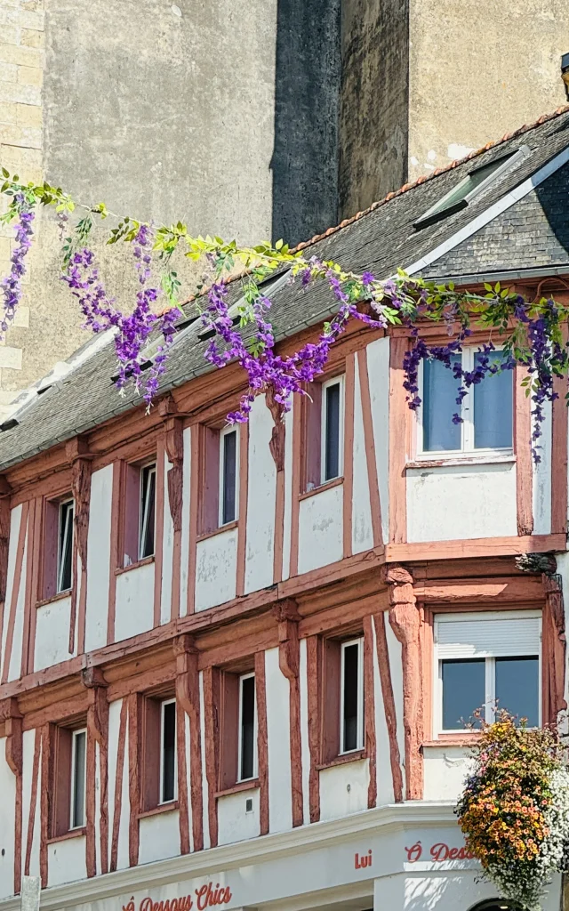 Maison en pan de bois faisant face aux Halles de Lannion avec les guirlandes fleuries installées en saison