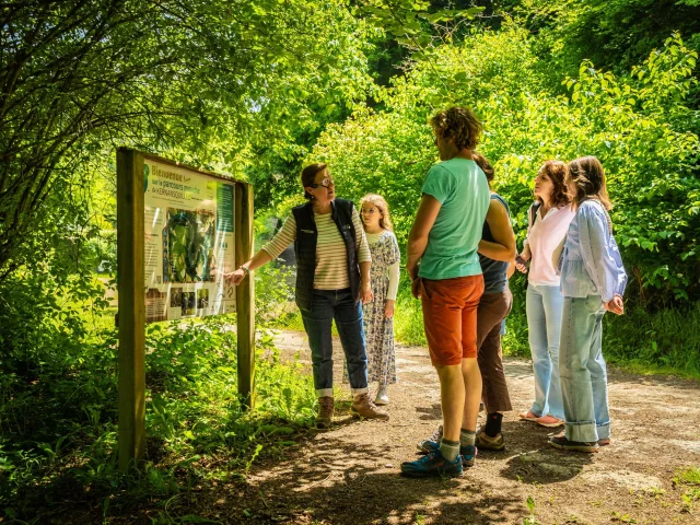 Balade ludique : le diable est à Kernansquillec : le groupe est devant le panneau de l'entrée du site écoutant les premiers commentaires de la guide