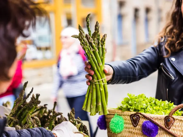 Une dame tenant une botte d'asperge sur le marché de Tréguier