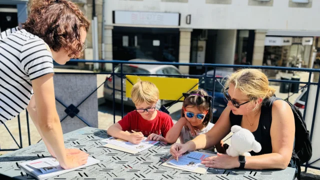 Balade Ludique de Lannion. La famille remplie le livret donné à l'occasion de la visite face aux Halles de Lannion.