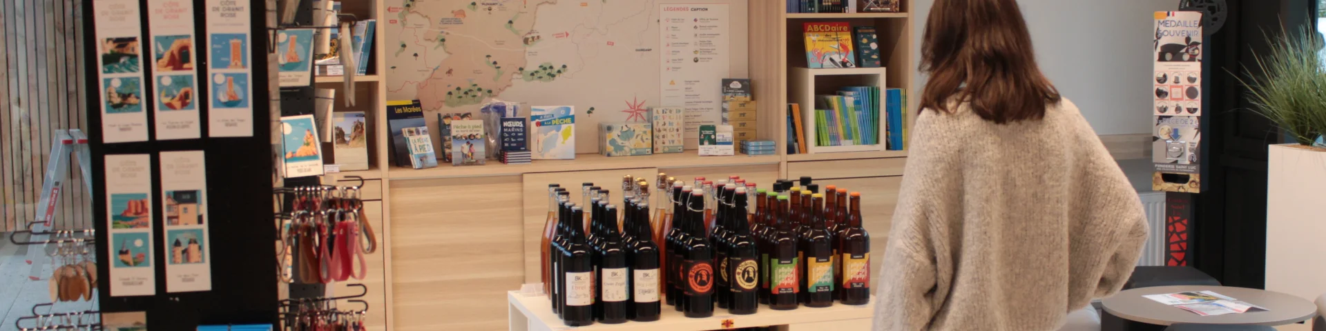 La Boutik de l'office de tourisme au Quai de Viarmes. Une personne est sur la photo qui regarde les produits exposés dans la boutique.