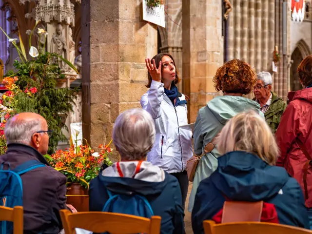 Une guide montre la nef du Elise à un groupe de touriste en visite guidée.