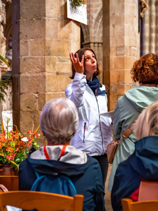 Une guide montre la nef du Elise à un groupe de touriste en visite guidée.