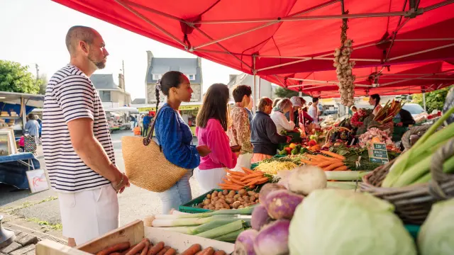 Des personnes font la queue devant l'étale d'un maraîcher sur le marché de Trébeurden