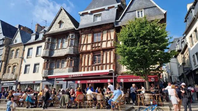 Des personnes sonte ne terrasse devant des maisons à pans de bois de la place du Général Leclerc à Lannion
