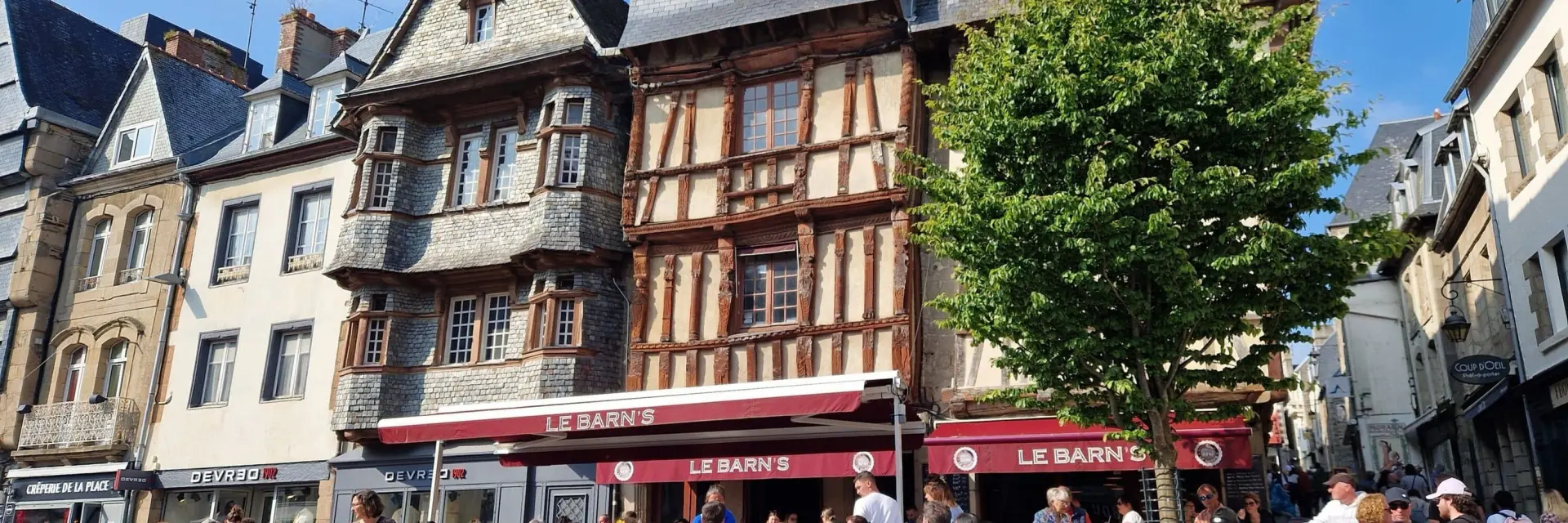 Des personnes sonte ne terrasse devant des maisons à pans de bois de la place du Général Leclerc à Lannion