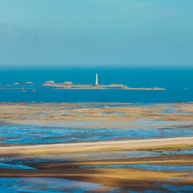 Vue du phare des Heaux, à Pleubian, entouré de la mer et du sable qui forment un zigzag au premier plan